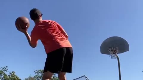 Guy Dribbles Two Basketballs and Throws Them in Basket While Balancing over Slackline