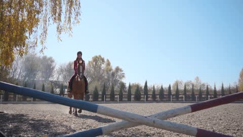 Young brunette Caucasian girl in pink clothes and horse riding helmet