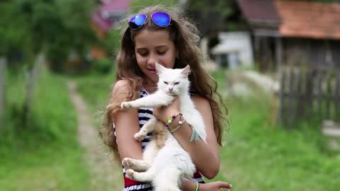 Beautiful girl holds in hands white cat and looks at the camera