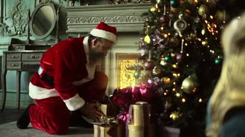 Santa puts presents under the Christmas tree