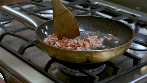 Frying diced bacon in a skillet