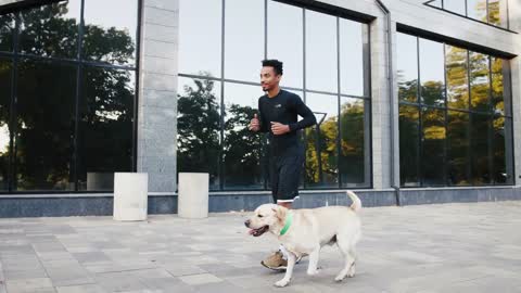 Young black man running with his white labrador dog in buseness city center