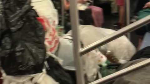 Trash bags and trash in subway car man sleeping