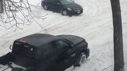 Stuck Car Struggles on Snowy Street