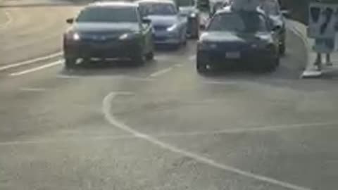 Small black car in traffic with white surf board