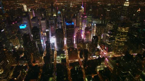 Tall city buildings and street lights illuminate at night