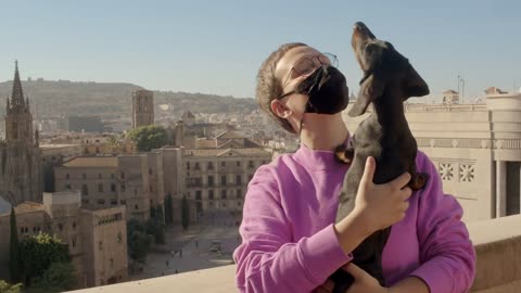 Woman with short haircut in a purple sweater and medical mask is holding a dachshund dog puppy