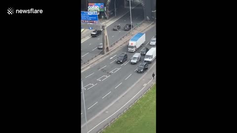 Ex-GOOSE me! Group of geese hold up traffic while crossing the busy Manchester road