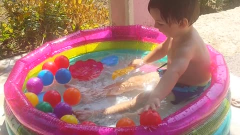 Playing babies with balls in the swimming pool