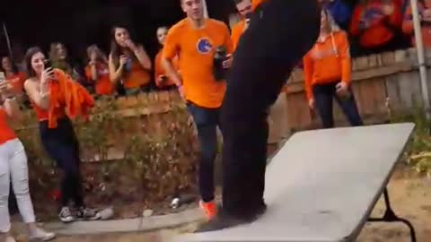 Music orange shirt black hat jumps off roof and breaks folding table