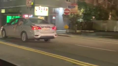 Man hanging out window of silver car