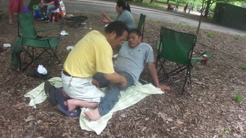 Luodong Massages Mexican Man's Foot And Leg At The Park