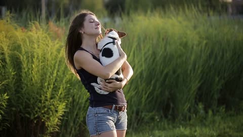 Woman beautiful young happy with long dark hair holding small dog in the garden