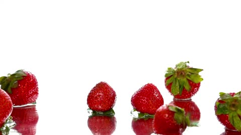 Strawberries falling on a surface on a white background