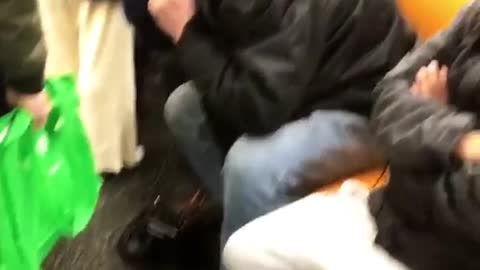 Man plays loud electric guitar with amp on ubway train