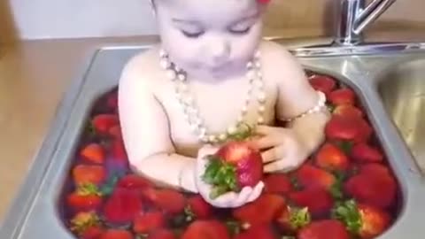 Little girl swims in strawberries.