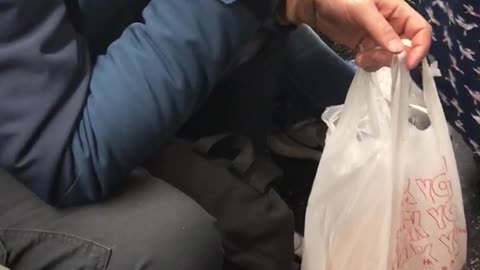 Old hat man eats bread food out of plastic grocery bag