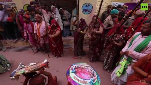 Indian women beat men with wooden sticks at Lathmar Holi festival