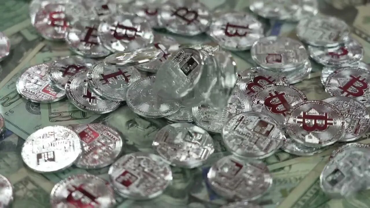 a slow motion view of dropping silver bitcoins over rotating us currency SBV 346729921 HD