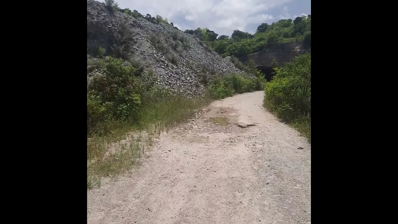 TUNEL SINISTRO DO RODOANEL NORTE TRILHA CERCADA DE MATO E RESTOS DE OBRA E PEDRAS GRANDES NO CAMINHO