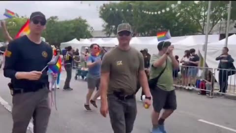 FBI marching in an LGBTQ pride parade waving a flag promoting the g*nital m*tilation of children