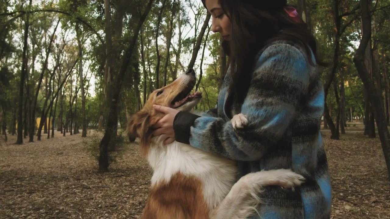 A woman pets her dog in the park