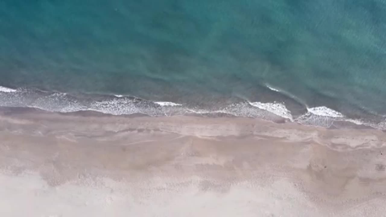 Top View of Breaking Waves on a Sandy Beach