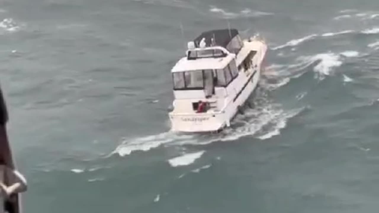 Nadador de resgate da USCG realizando um resgate no que parecem ser ondas moderadas