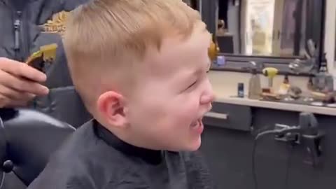 Cute baby smiling in a salon while cutting his hair.