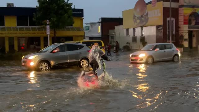 Guys Ride Through Flooded Streets on Electric Scooters