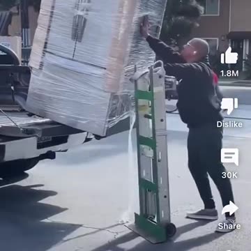 Man unloads refrigerator off pickup truck by himself