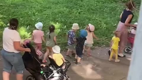 Children from a kindergarten in St. Petersburg walking while tied to a string