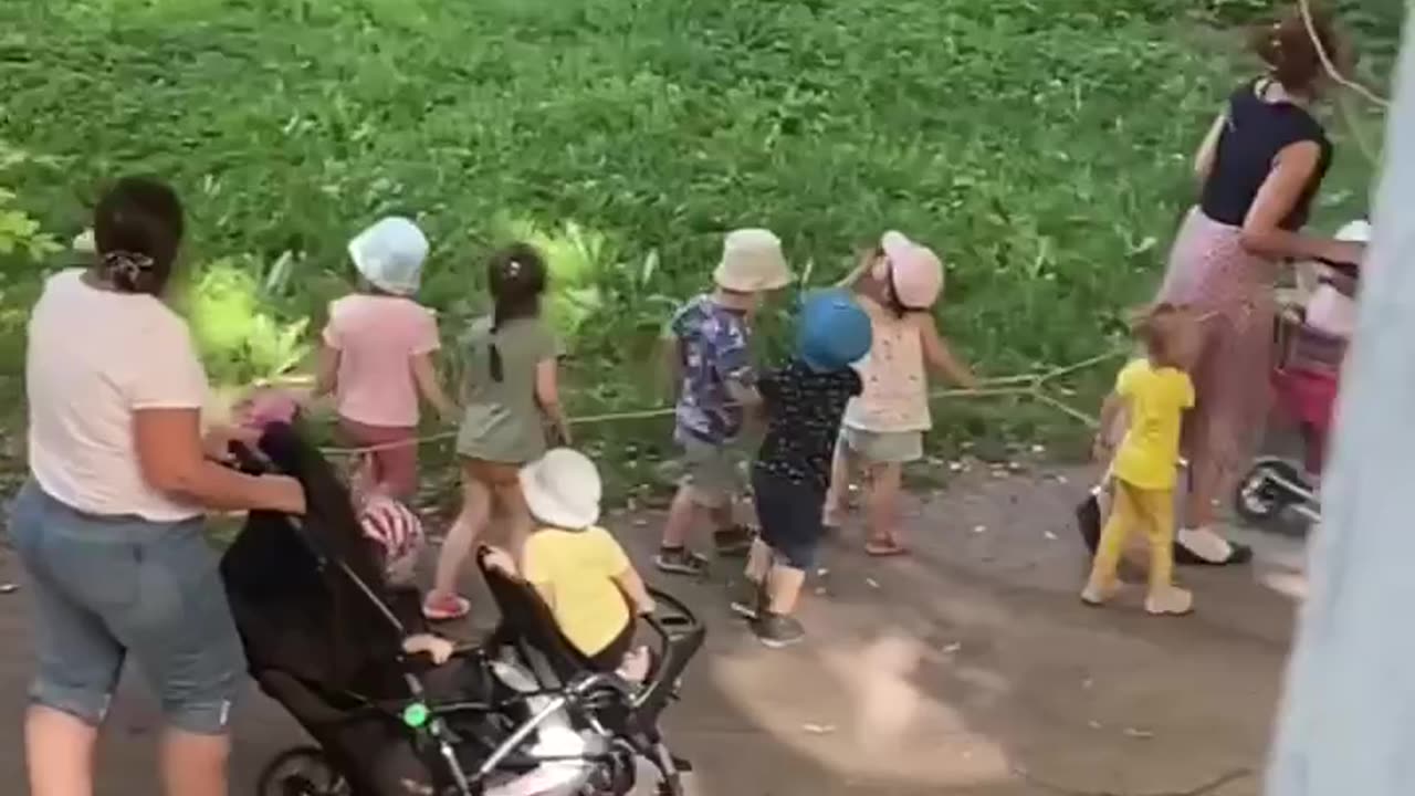 Children from a kindergarten in St. Petersburg walking while tied to a string