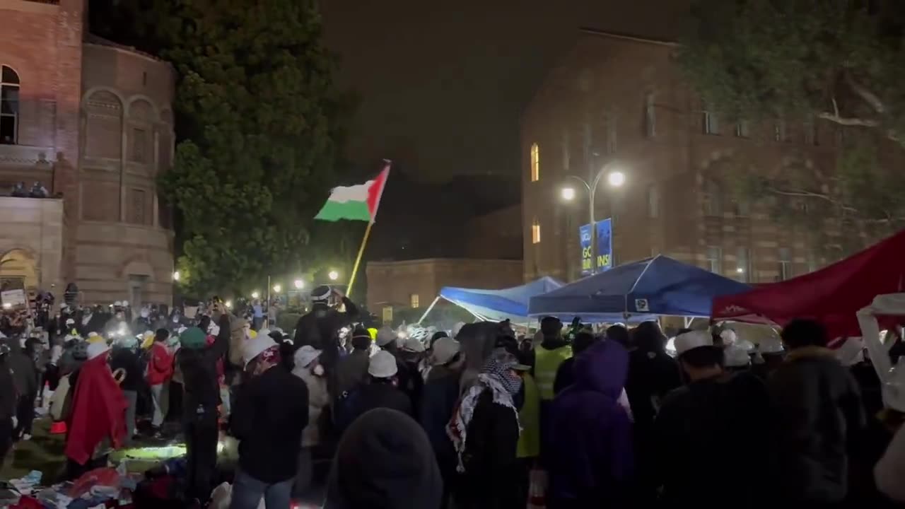 Protesters chant “Hold the Line” as tear gas is fired into the UCLA encampment