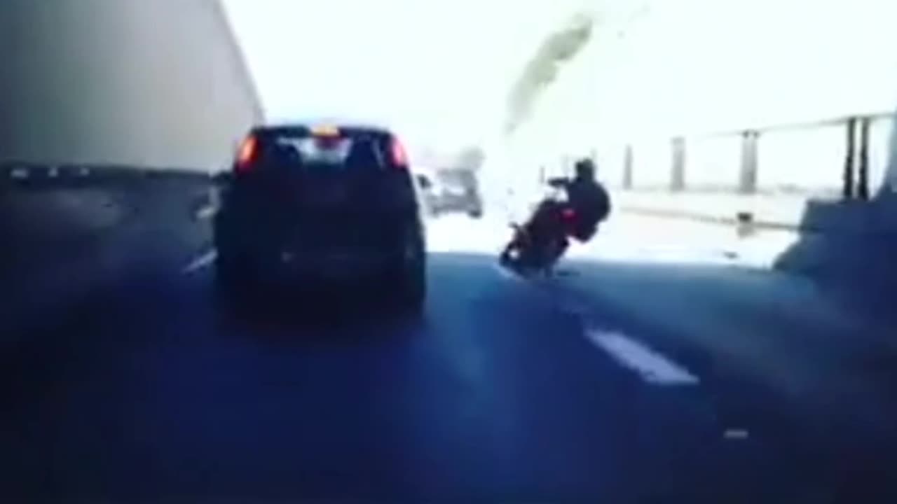 Kicks a car and crashes his bike.