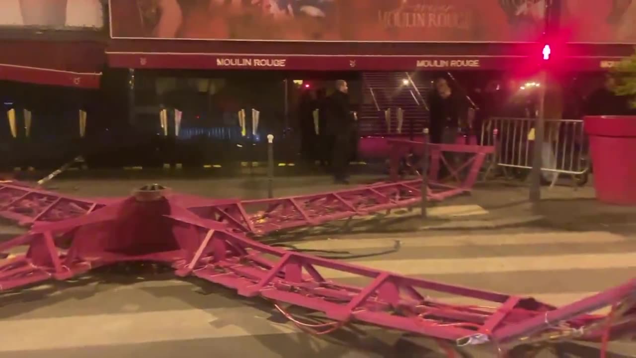 In Paris at night, the windmill blades of the famous Moulin Rouge cabaret