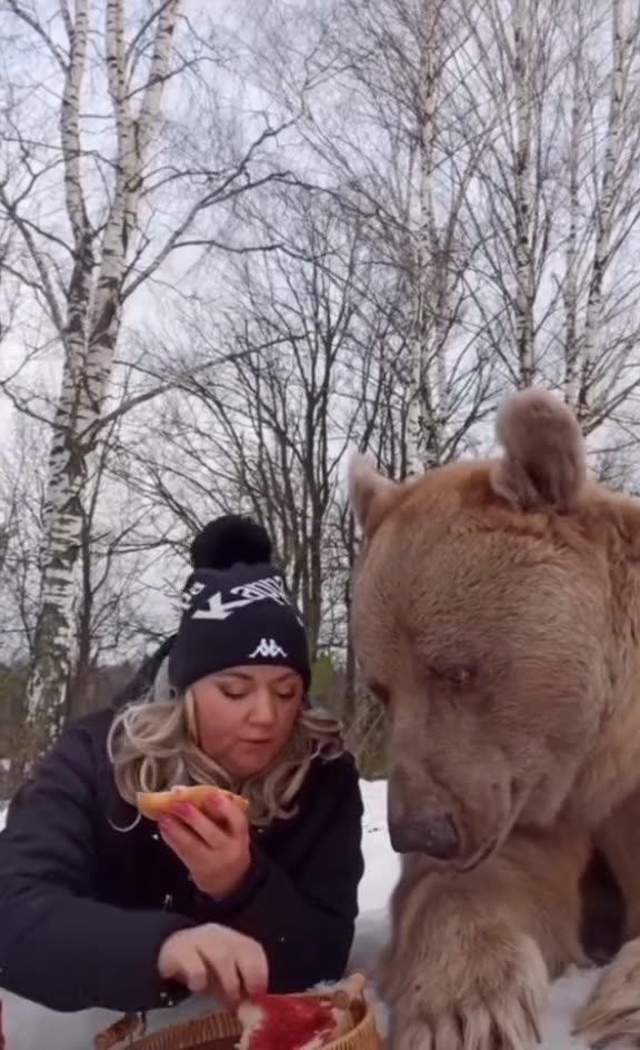 A woman with a bear, eating bread and jam