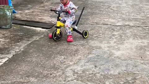 Funny baby with his yellow bicycle