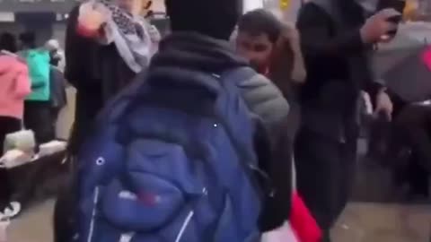 A man attempts to pass through a pro-Palestine rally with a Canadian flag and is