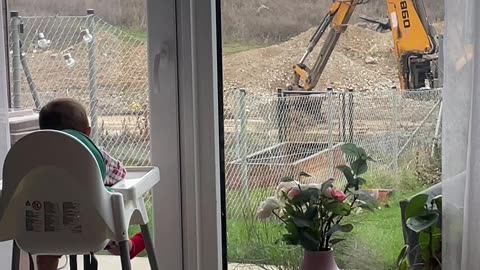 A Little Baby Enjoys Watching an Excavator at Work