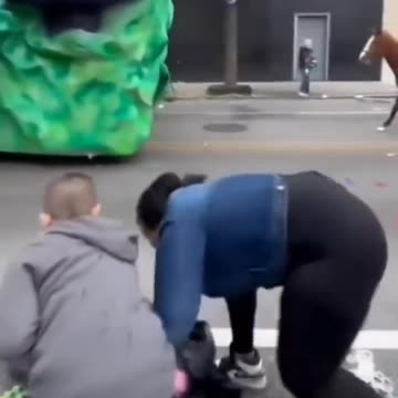 At a parade, blk woman steals bag of toys from white kid.