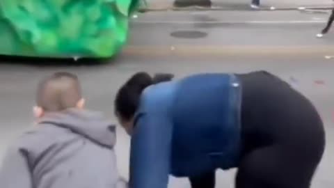 At a parade, blk woman steals bag of toys from white kid.