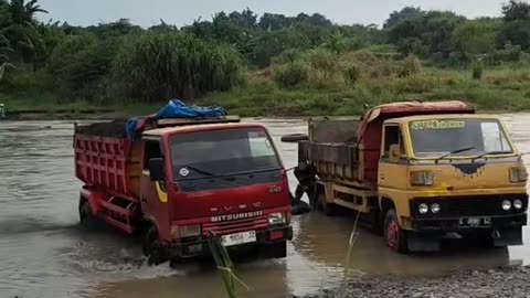 trucks loaded with sand come out of the river