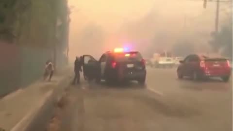 Los Angeles police help people fleeing a fire on foot in Pacific Palisades.