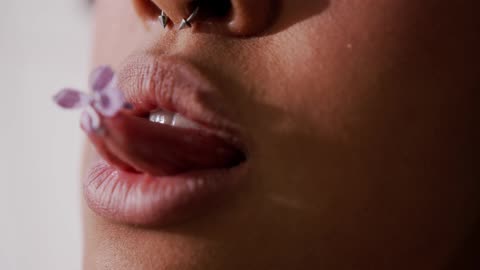 Girl With Nose Ring Eats A Flower Petal