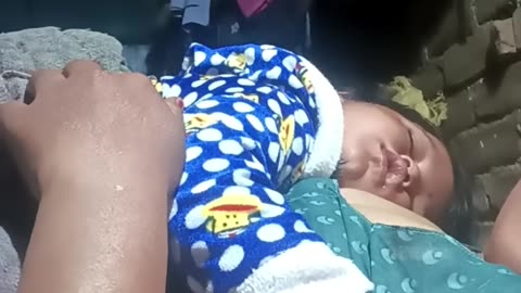 A mother is breastfeeding her baby at night