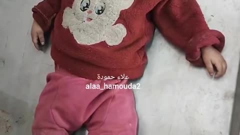 A small child lies alone inside a morgue refrigerator at Al-Aqsa Martyrs Hospital