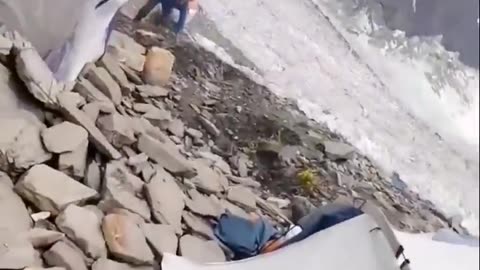A giant rock rolling down a mountain just misses a camp and a couple people.