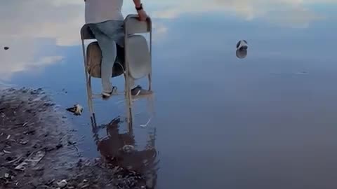 Man Uses Folding Chairs To Cross Water