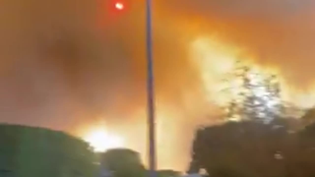 A rapidly advancing wildfire erupted in a Los Angeles suburb, destroying structures